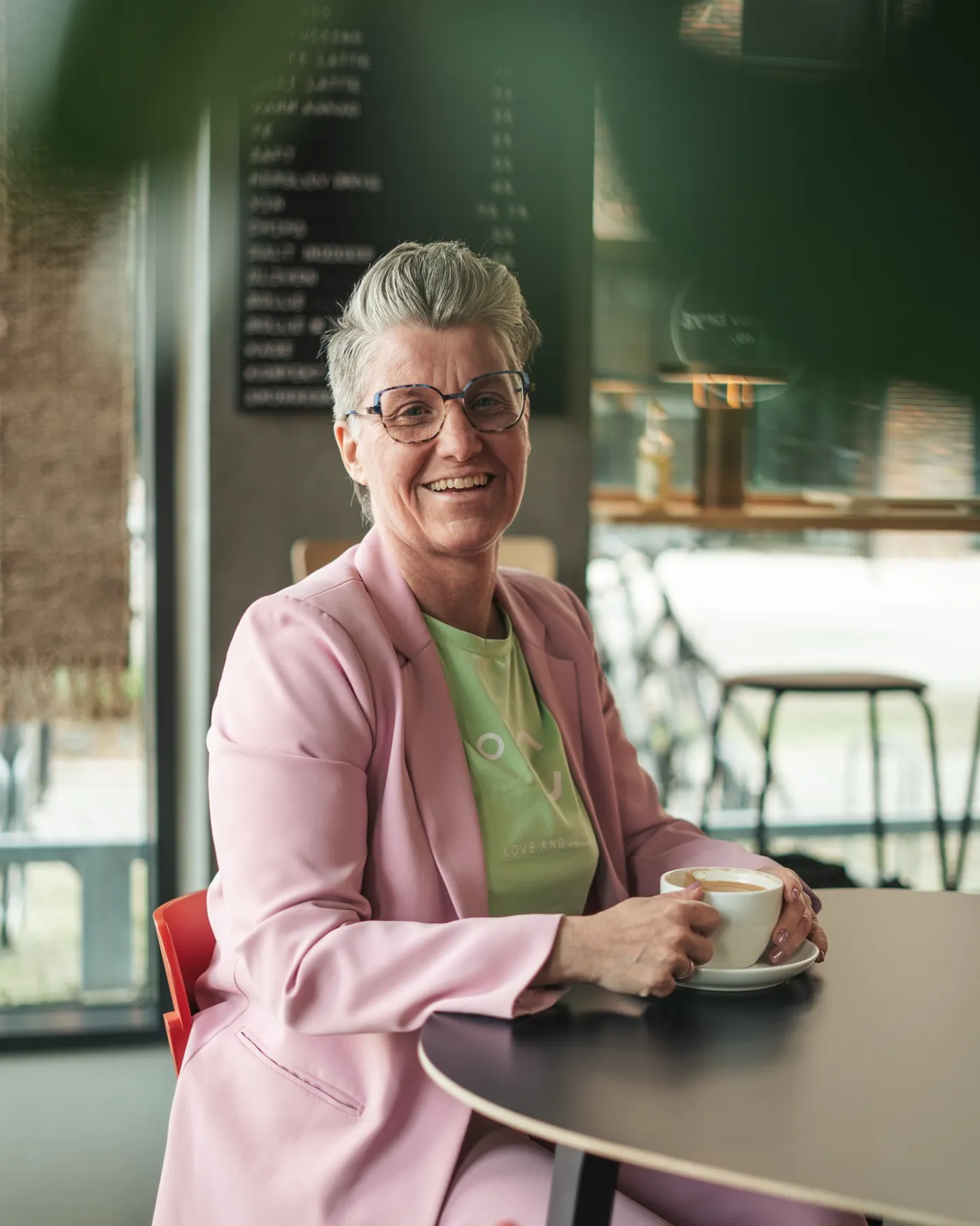 Fotografi af Mads Dyg: Kvinde i lyserød blazer på café